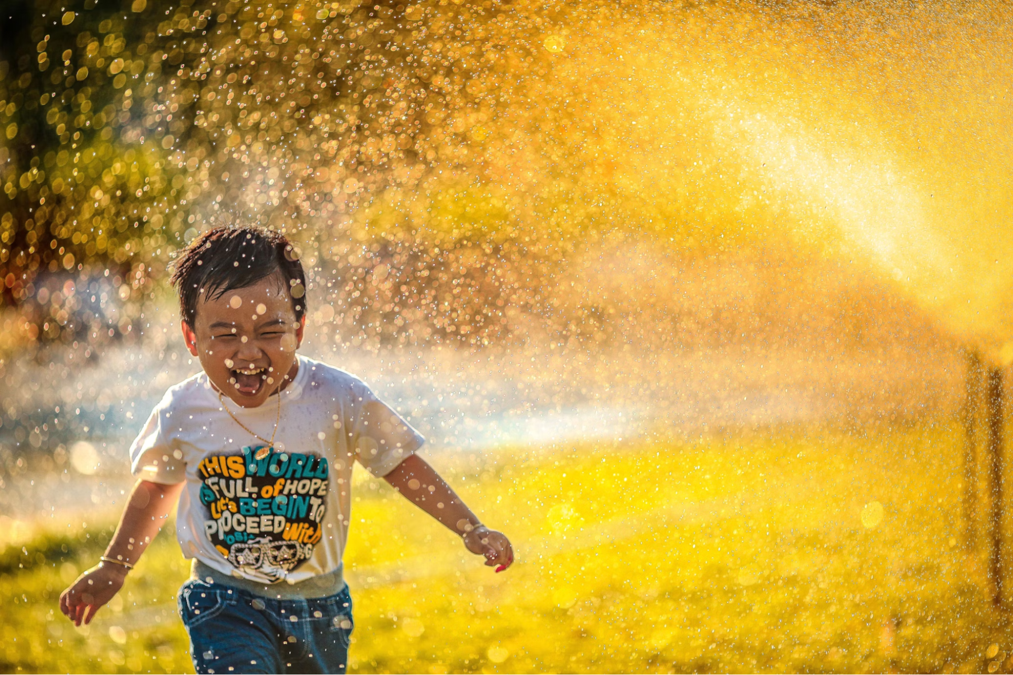 Child running through water sprinkler